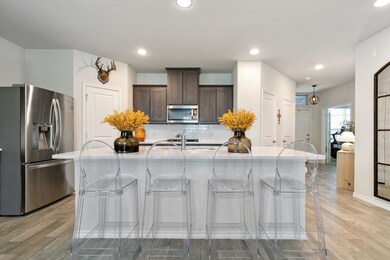 Kitchen featuring light hardwood / wood-style floors, an island with sink, backsplash, a kitchen bar, and appliances with stainless steel finishes
