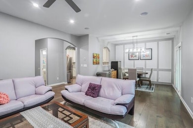 Living room featuring arched walkways, ceiling fan, wood finished floors, recessed lighting, and a chandelier
