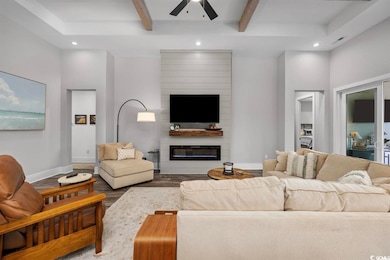 Living room featuring a ceiling fan, dark wood finished floors, recessed lighting, beamed ceiling, and a large fireplace