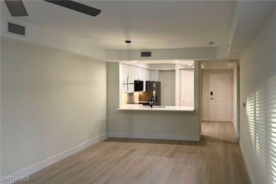 Kitchen featuring light countertops, light wood-type flooring, a peninsula, white cabinetry, and recessed lighting