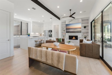 Living room featuring a ceiling fan, light wood f