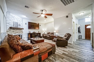 The front door opens to a foyer with a soaring ceiling and then delivers guests to this inviting family room with brand new wood-look tile flooring, neutral grey paint, crisp white crown and chair rail molding, and a lighted ceiling fan.