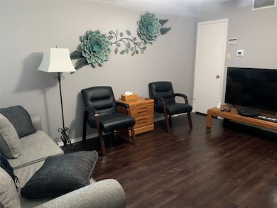 Living area featuring dark wood-type flooring and baseboards