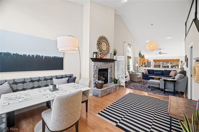 Living room featuring a stone fireplace, wood-type flooring, ceiling fan, and high vaulted ceiling