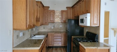 Kitchen with gas stove, white microwave, a sink, t
