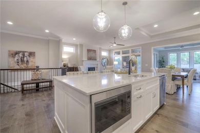 Kitchen with white cabinets, hardwood / wood-style flooring, sink, a kitchen island with sink, and appliances with stainless steel finishes