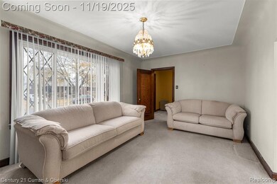 Carpeted living area with a chandelier and baseboards