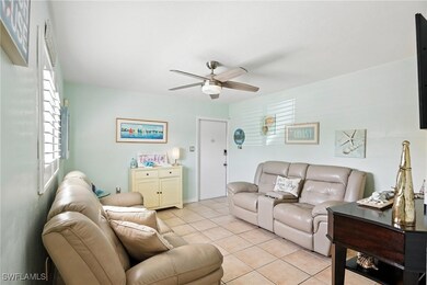 Living room with ceiling fan and light tile patter