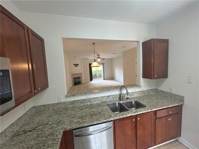 Kitchen featuring stainless steel dishwasher, a fireplace, light stone countertops, ceiling fan, and decorative light fixtures