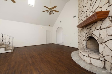 Unfurnished living room with a ceiling fan, high vaulted ceiling, wood finished floors, and arched walkways