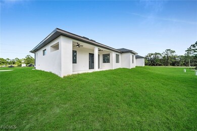 Back of house featuring ceiling fan, stucco siding, a yard, and a patio area