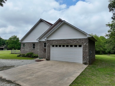 View of front of property with a front yard, brick siding, an attached garage, and driveway
