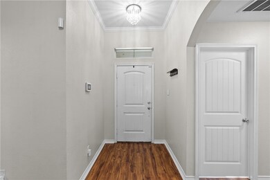 Doorway to outside with crown molding, wood finished floors, arched walkways, and a chandelier