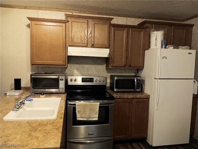Kitchen with stainless steel appliances, under cabinet range hood, and brown cabinets