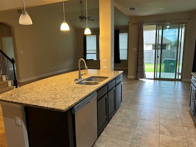 Kitchen with a kitchen island with sink, decorative light fixtures, dark cabinets, dishwasher, and open floor plan