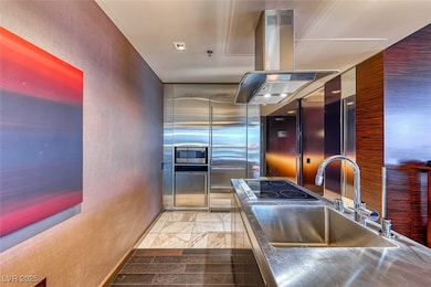 Kitchen featuring stainless steel countertops, a sink, island exhaust hood, appliances with stainless steel finishes, and a textured wall