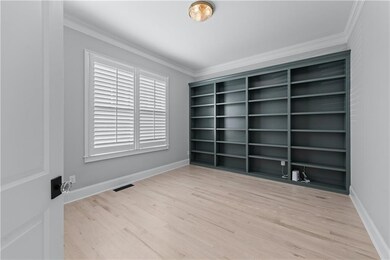 Empty room featuring crown molding, wood finished floors, and baseboards