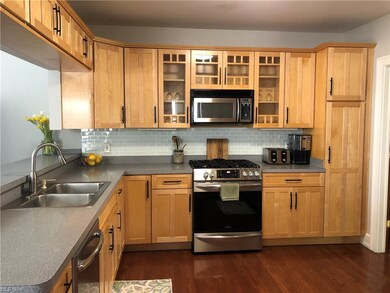 Functional kitchen is open to the family room and dining areas.  It has hardwood flooring, maple cabinetry, stainless steel appliances and decorative glass tile backsplash.