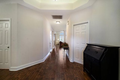 Hallway with dark wood-type flooring and baseboar