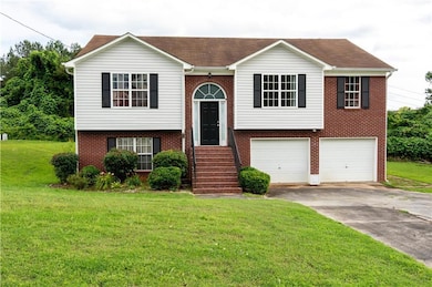 Split foyer home with concrete driveway, a front yard, a garage, and brick siding