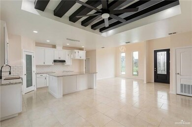 Kitchen with under cabinet range hood, tasteful backsplash, a ceiling fan, open floor plan, and light stone countertops