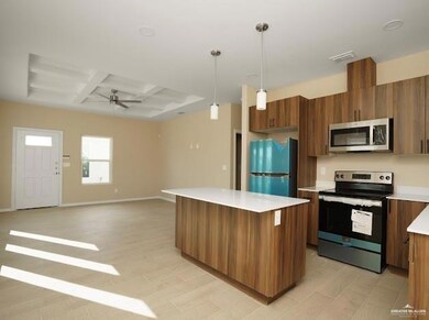 Kitchen with brown cabinets, light countertops, appliances with stainless steel finishes, a kitchen island, and coffered ceiling