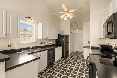 Kitchen featuring a sink, black appliances, dark countertops, and white cabinetry