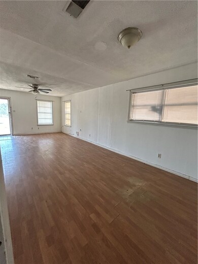Unfurnished room featuring a textured ceiling, plenty of natural light, and dark wood finished floors