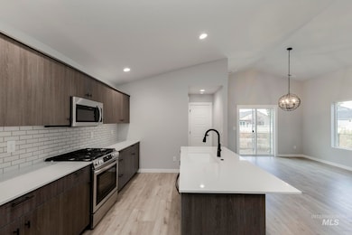 Kitchen with stainless steel appliances, light wood-style floors, backsplash, lofted ceiling, and modern cabinets