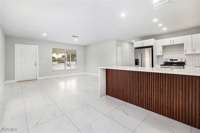 Kitchen featuring light stone counters, light marble finish flooring, white cabinetry, appliances with stainless steel finishes, and recessed lighting