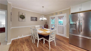 Dining area featuring light wood-style flooring, a chandelier, and ornamental molding