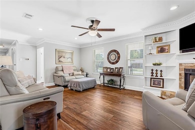 Living area featuring recessed lighting, crown molding, wood finished floors, a fireplace, and ceiling fan