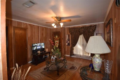 Living room featuring ceiling fan, wood walls, har