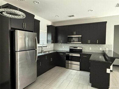 Kitchen featuring visible vents, appliances with stainless steel finishes, a sink, dark cabinets, and a peninsula