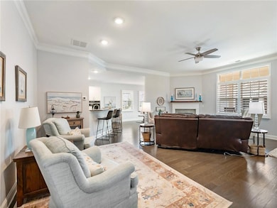Living area with ceiling fan, wood finished floors, crown molding, recessed lighting, and a fireplace