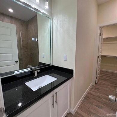 Bathroom featuring vanity, a shower stall, a spacious closet, and wood finished floors