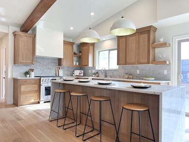 Kitchen with custom cabinetry, quartz countertops, breakfast bar, new appliances, mountain views, and a door out to the deck.