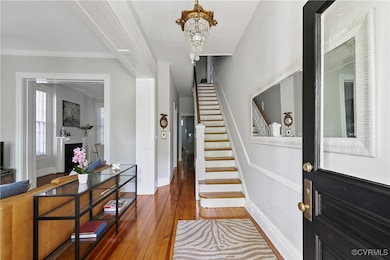 Foyer entrance featuring hardwood / wood-style floors, a chandelier, and crown molding