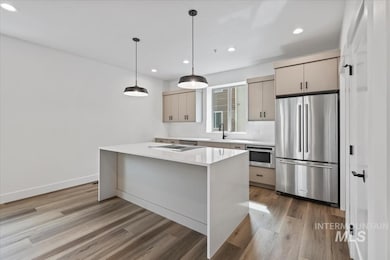 Kitchen with appliances with stainless steel finishes, light stone counters, hanging light fixtures, recessed lighting, and light wood finished floors