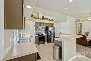 Kitchen with stainless steel appliances, a textured ceiling, light countertops, a kitchen island, and recessed lighting