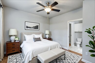 Bedroom with wood finished floors, connected bathroom, and a ceiling fan