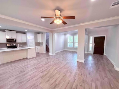 Unfurnished living room with ornamental molding, light wood-type flooring, ceiling fan, recessed lighting, and stairs