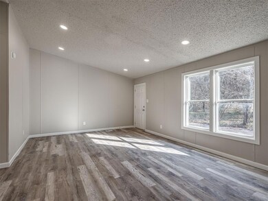 Unfurnished room with a textured ceiling and hardw