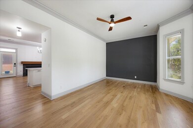Spare room with light wood-type flooring, crown molding, a ceiling fan, and baseboards