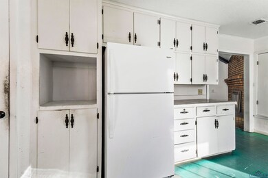 Kitchen with a fireplace, a textured ceiling, whit