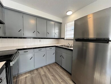 This is a view of the kitchen, freshly painted, also including a refrigerator, oven, and stove. Notice all of the generous cabinet space. All appliances are brand new.