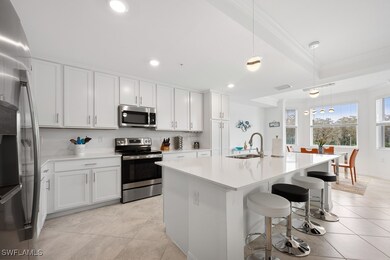 Kitchen with pendant lighting, stainless steel appliances, an island with sink, white cabinetry, and a breakfast bar