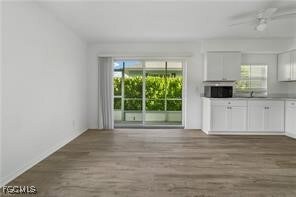 Unfurnished living room featuring plenty of natural light, wood finished floors, and a ceiling fan