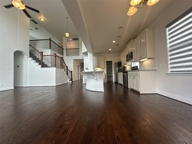 Unfurnished living room with dark wood finished floors, stairway, ceiling fan, arched walkways, and a chandelier