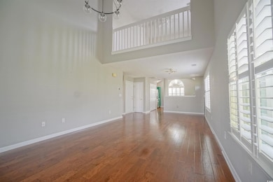 Unfurnished living room with a chandelier, a towering ceiling, hardwood / wood-style floors, and baseboards
